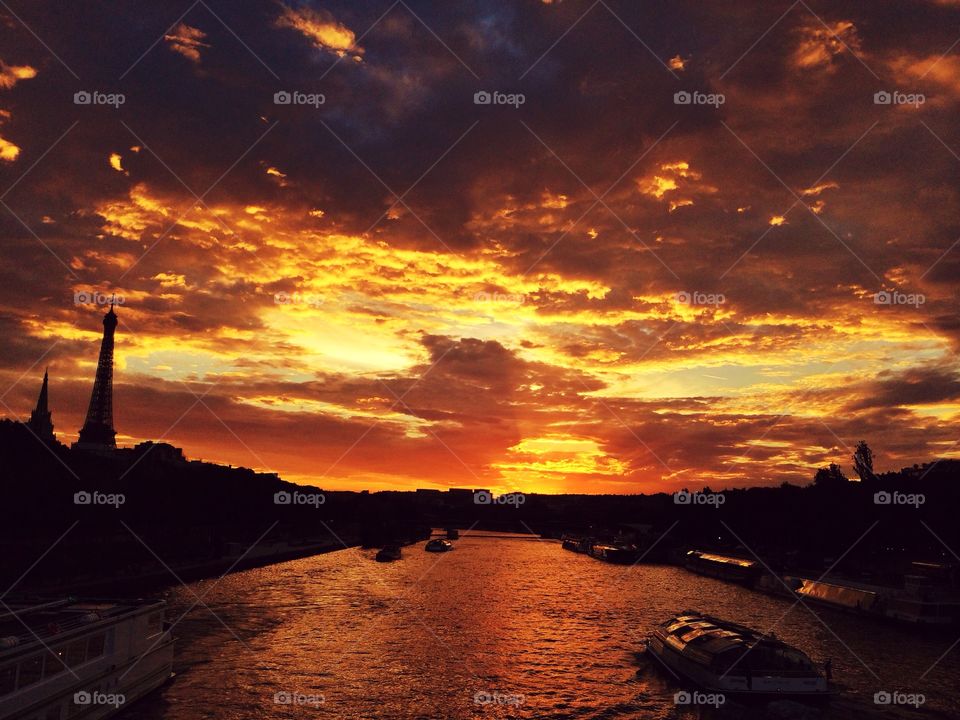 Sunset in The City of Love. A sunset in Paris. Sun sets over the Seine river with the Eiffel Tower on the left side.