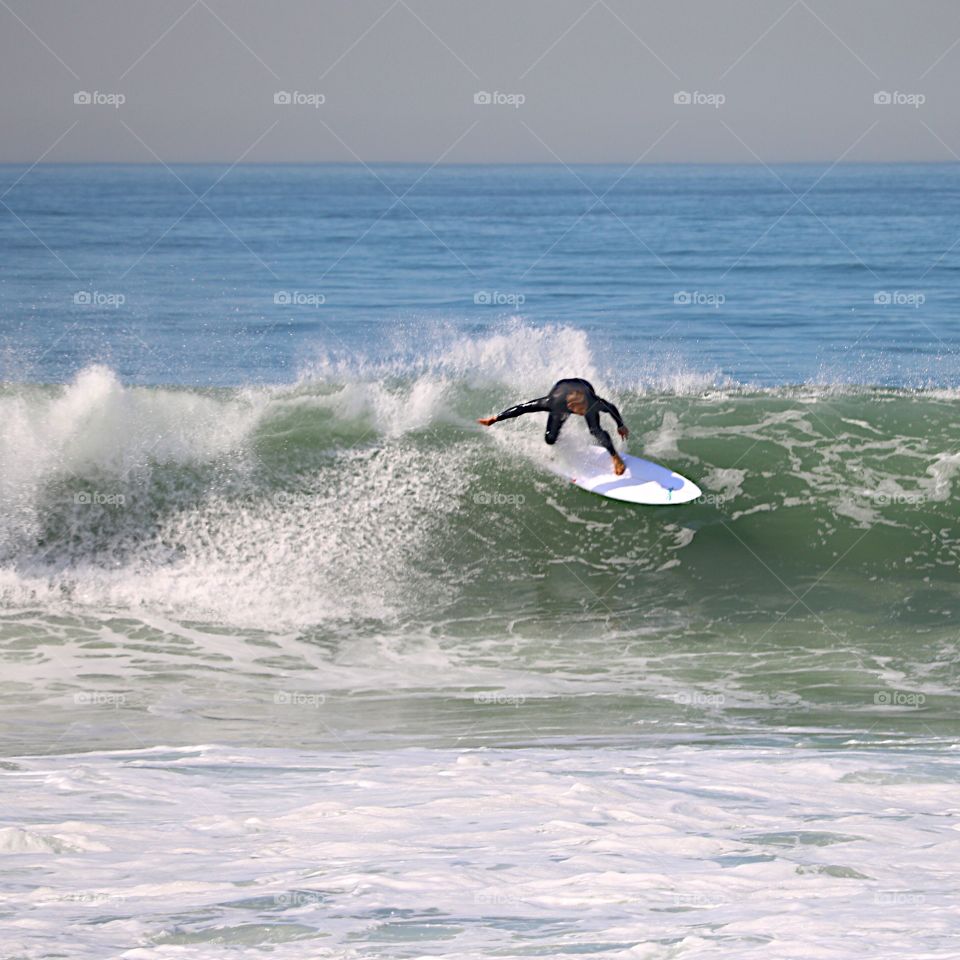 Surfer riding a wave also showing his shadow on his surfboard.  Manhattan Beach, CA