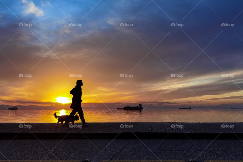 Silhouettes of a girl and a dog walking on the seaside under the sunset light of Thessaloniki. Rules of third and silhouettes, two of my favorite techniques in photography.