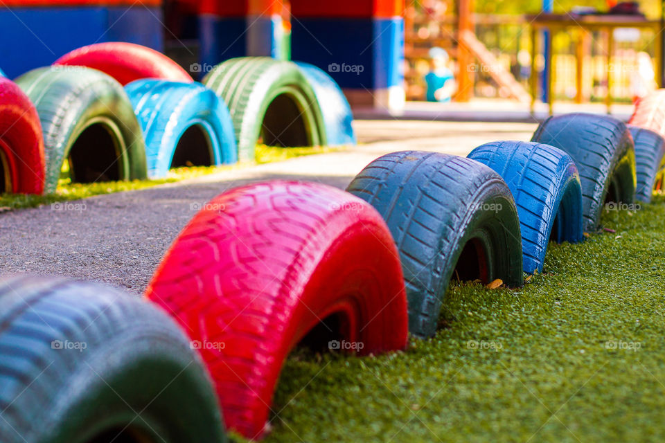 Recycled old car tires are painted and used on a playground. Great way to look after the earth. Different vibrant colors.