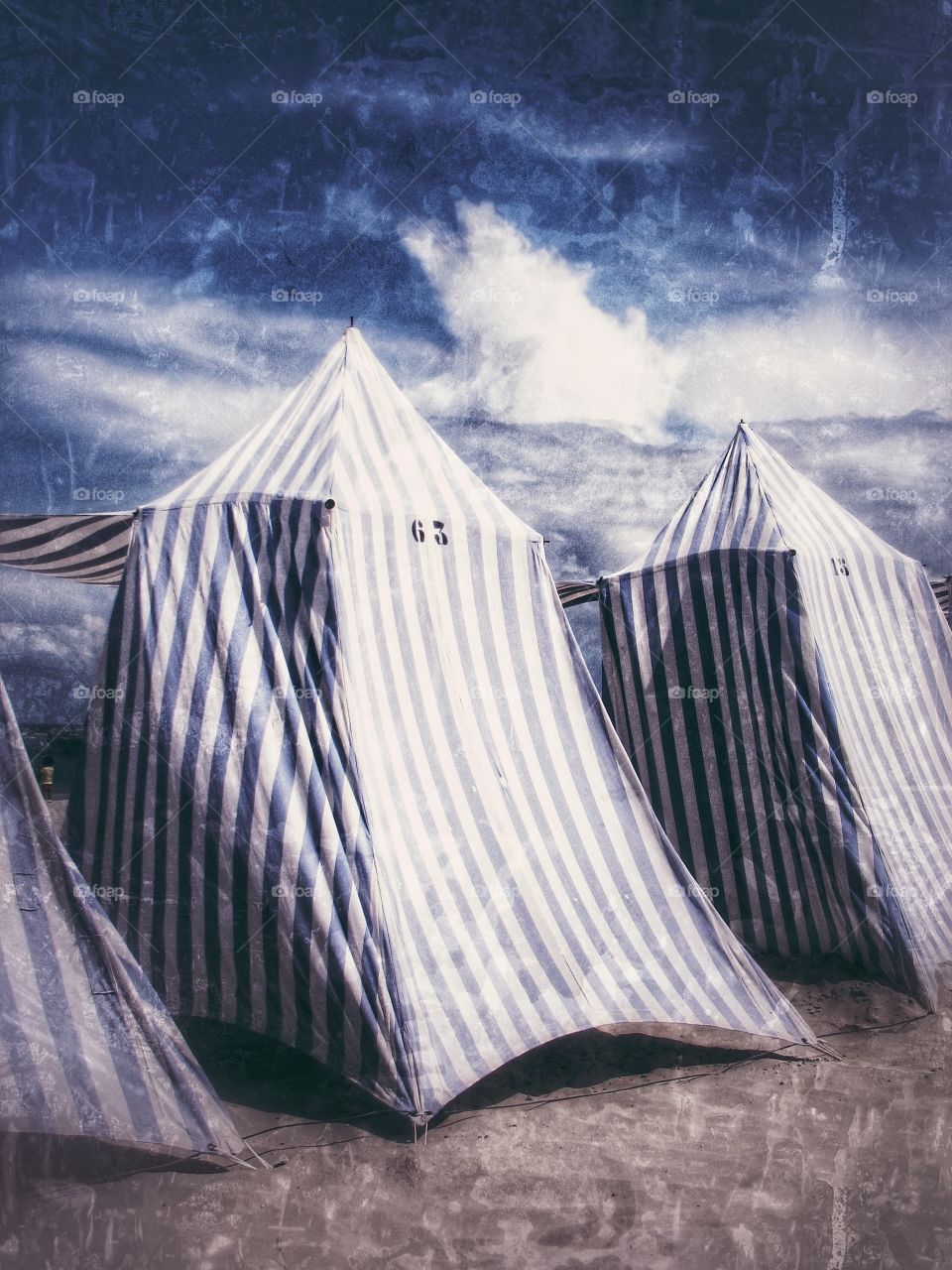 Striped Beach Tents. Blue and white stripy beach tents on a white, sand beach under a blue sky on a summer's day with an added texture.