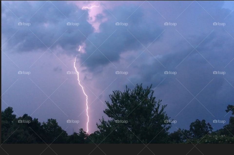 Lightning strike against tree line 