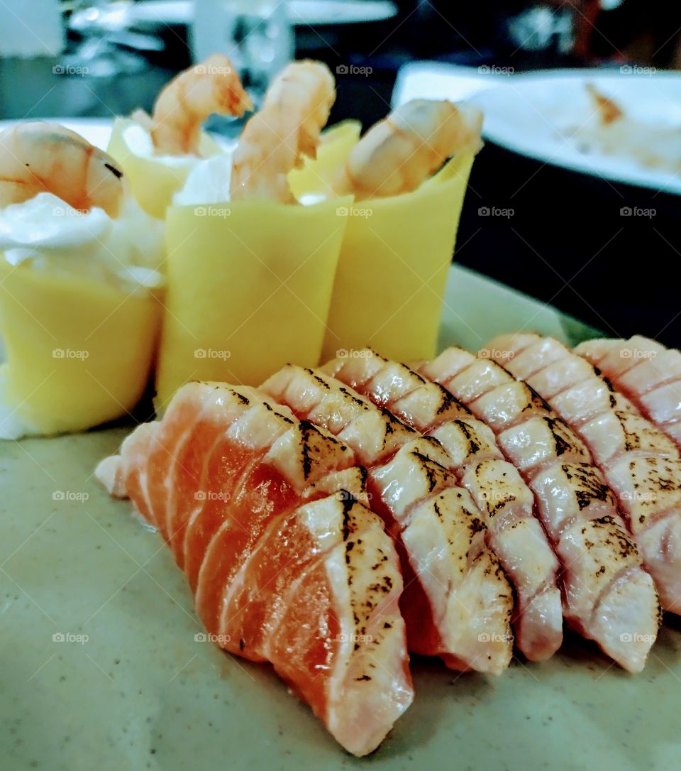 Salmão flambado... Ao fundo, manga com creme e camarão.