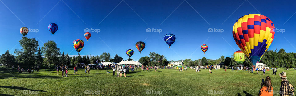 Balloon landscape - a wide shot of the take off field with the balloons floating in the clear, blue sky 