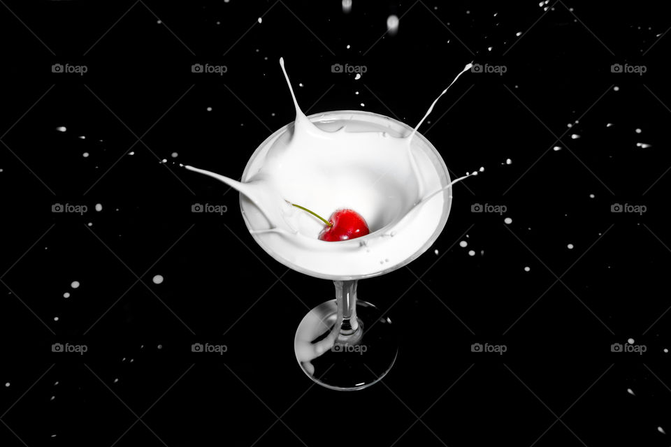 Fresh cherry falling into milk