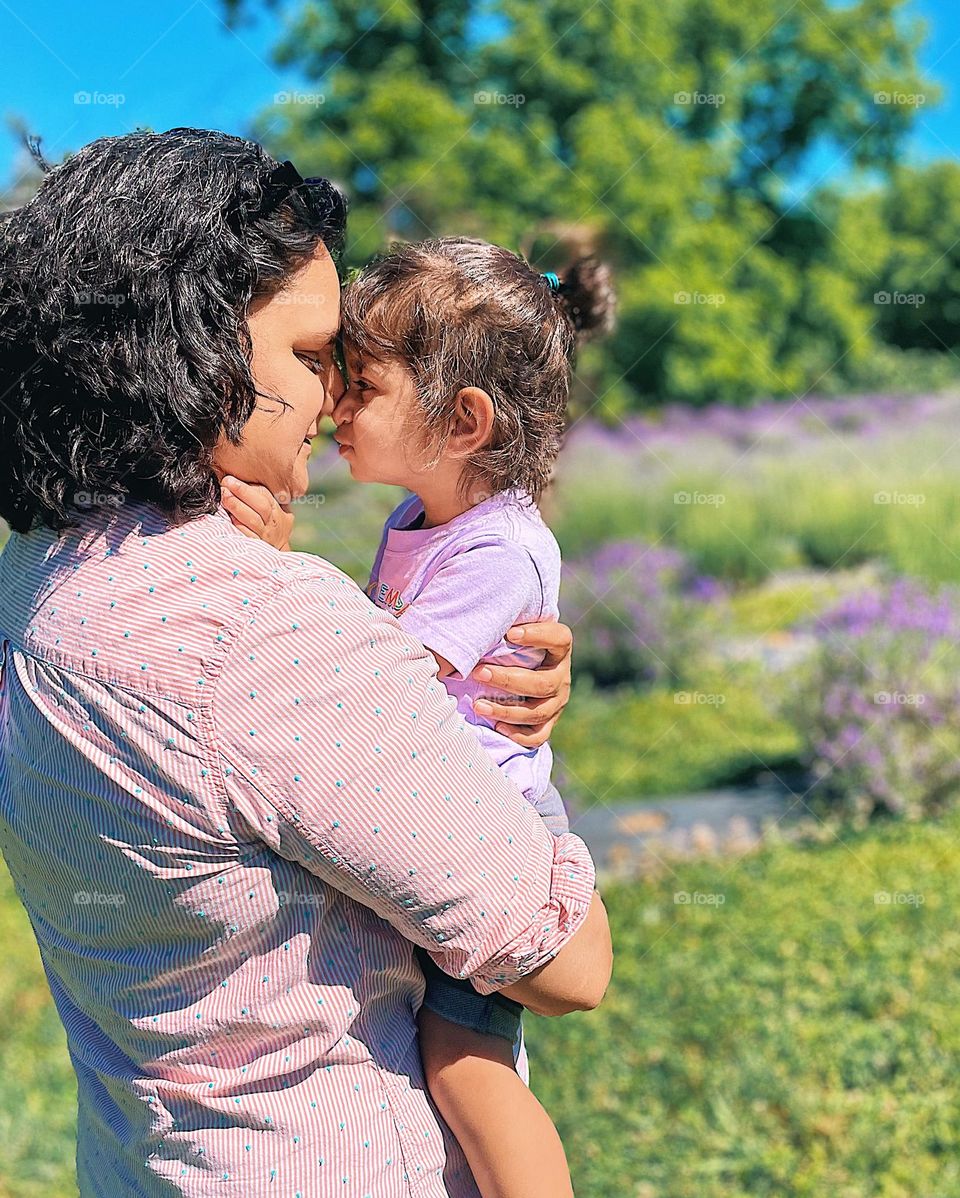 Mother holding daughter in lavender field, hair is the best accessory, face to face with hair all over the place, mother and daughter face to face, long haired beauties in the lavender field, wildflowers and women