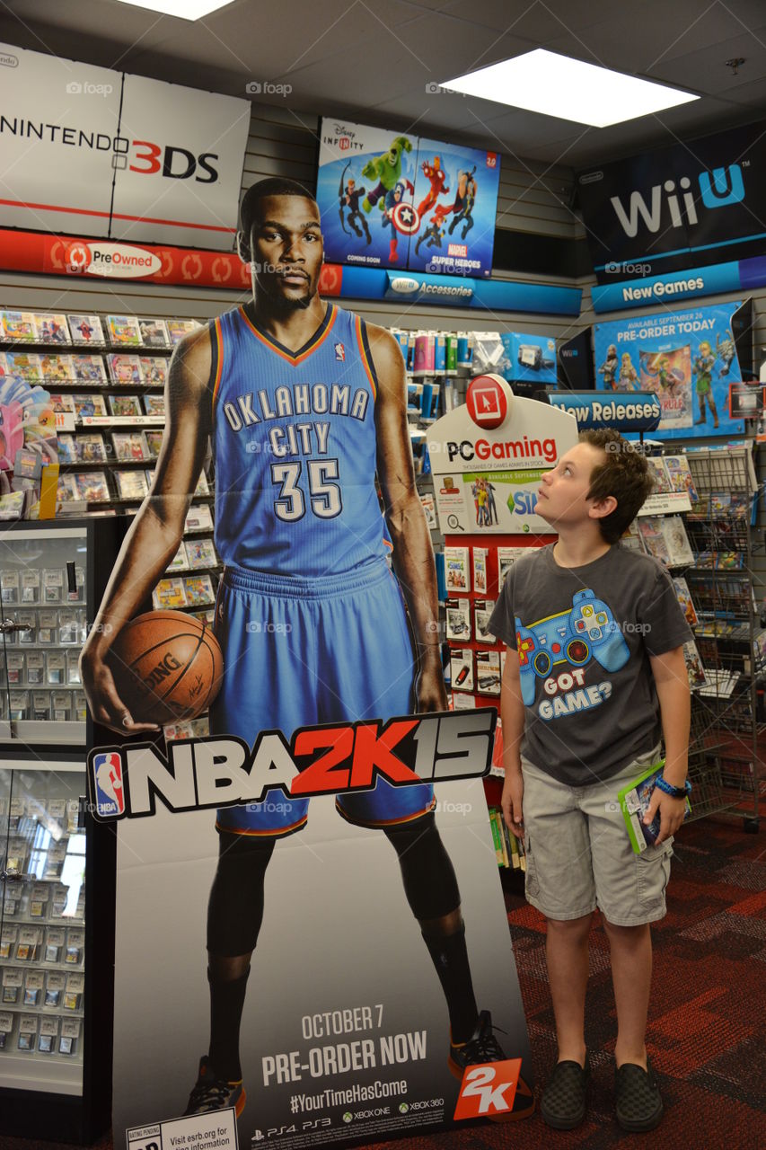 Teenager boy standing in shop and looking at basketball player photograph