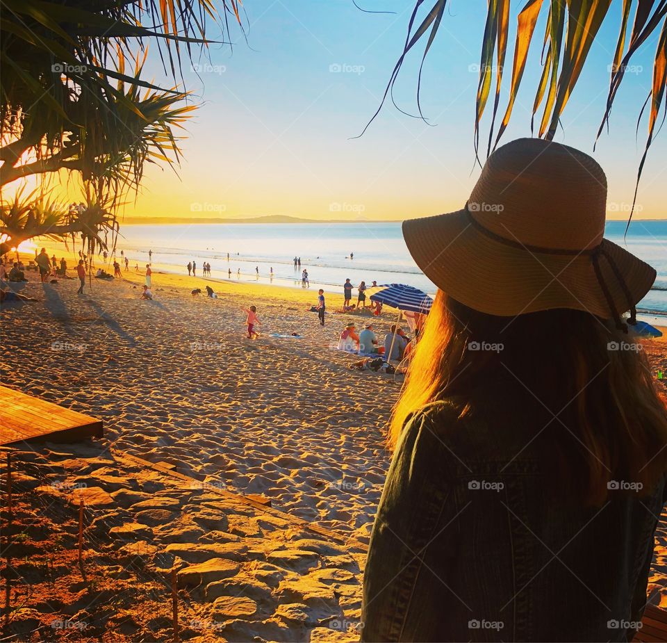 Looking at the beach at sunset girl with hat 