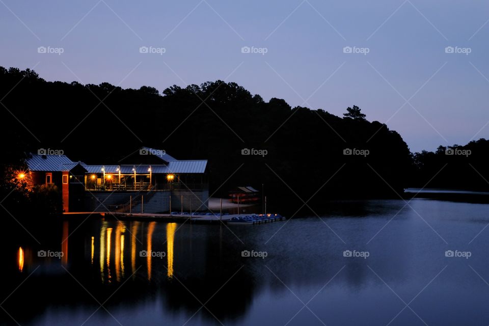 Foap, Light: Natural vs Artificial - the lights from a boathouse cast vivid reflections in the water at Lake Johnson Park in Raleigh, North Carolina.