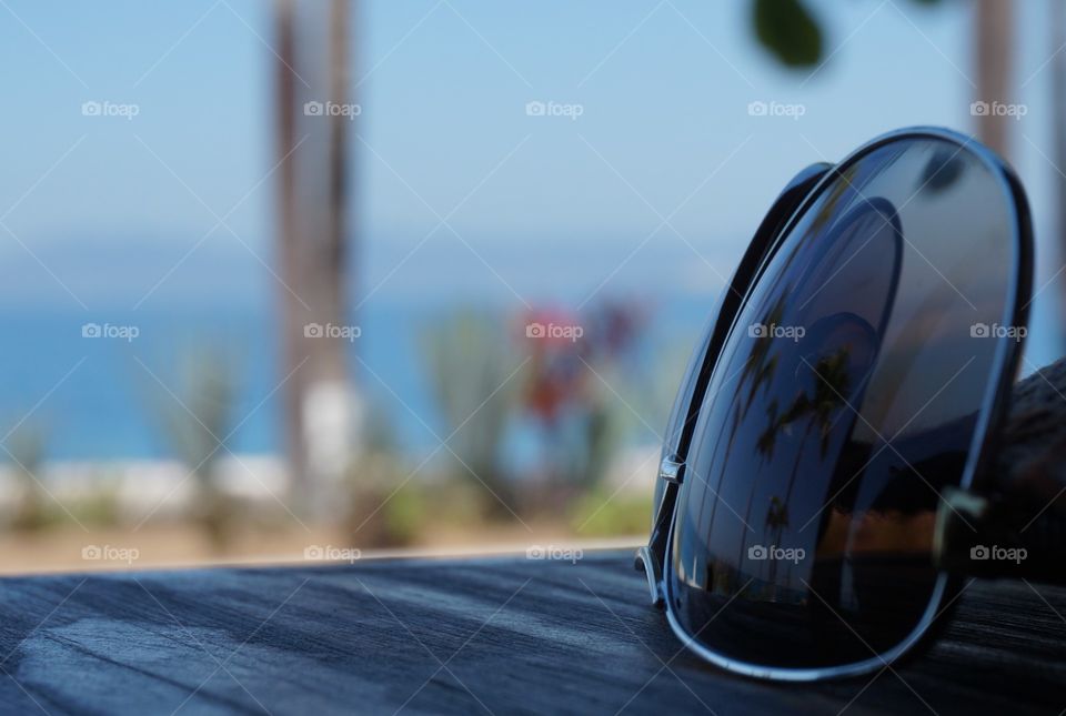 Palm trees and beach reflected in sunglasses on wood plank table.  Photo taken in Puerto Vallarta, Mexico 