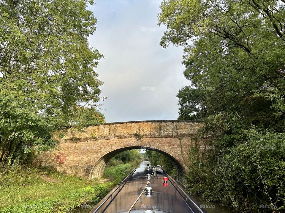 About to cruise under brick bridge 38 along Oxford canal near Brinklow Marina in England narrowboat vacation holiday beautiful sunny sky weather trees historical waterway