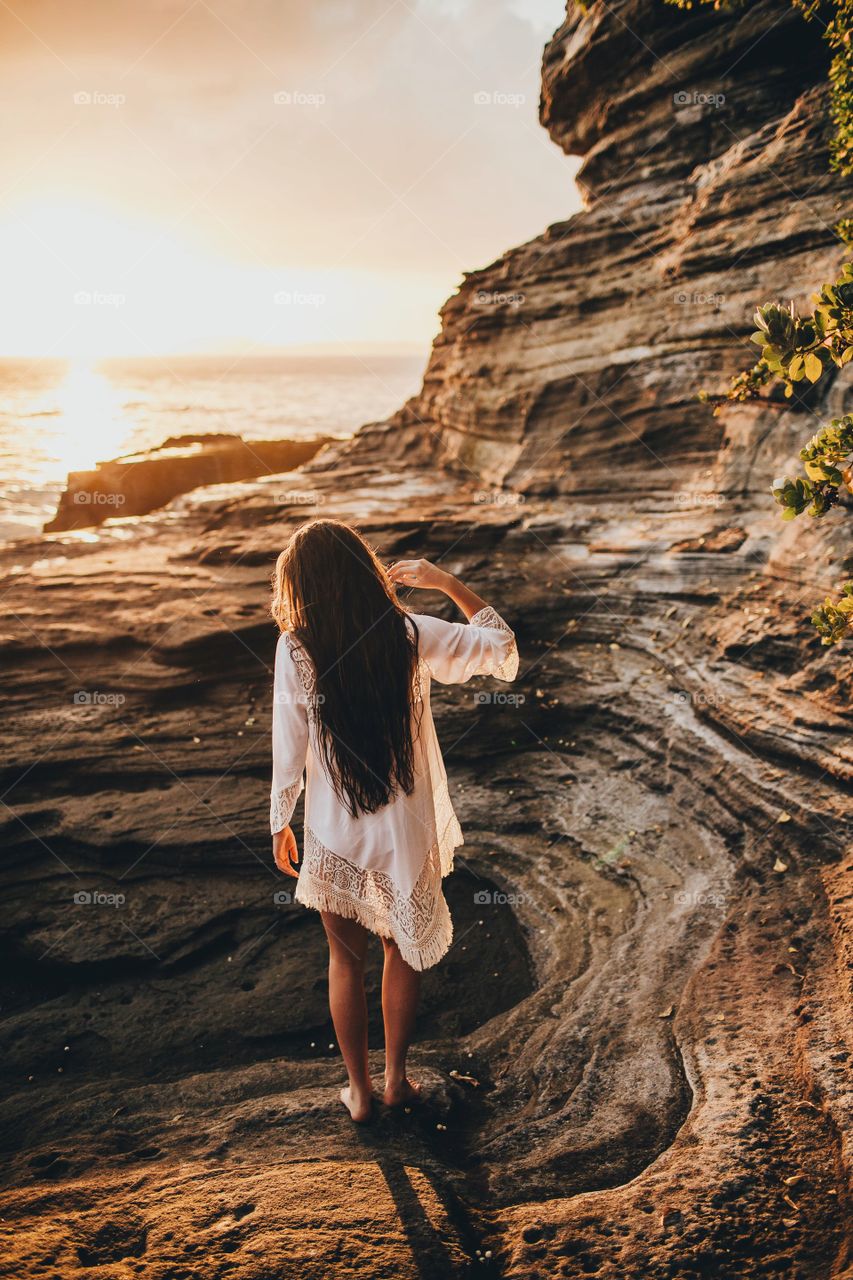 Girl explores cove at sunset.
