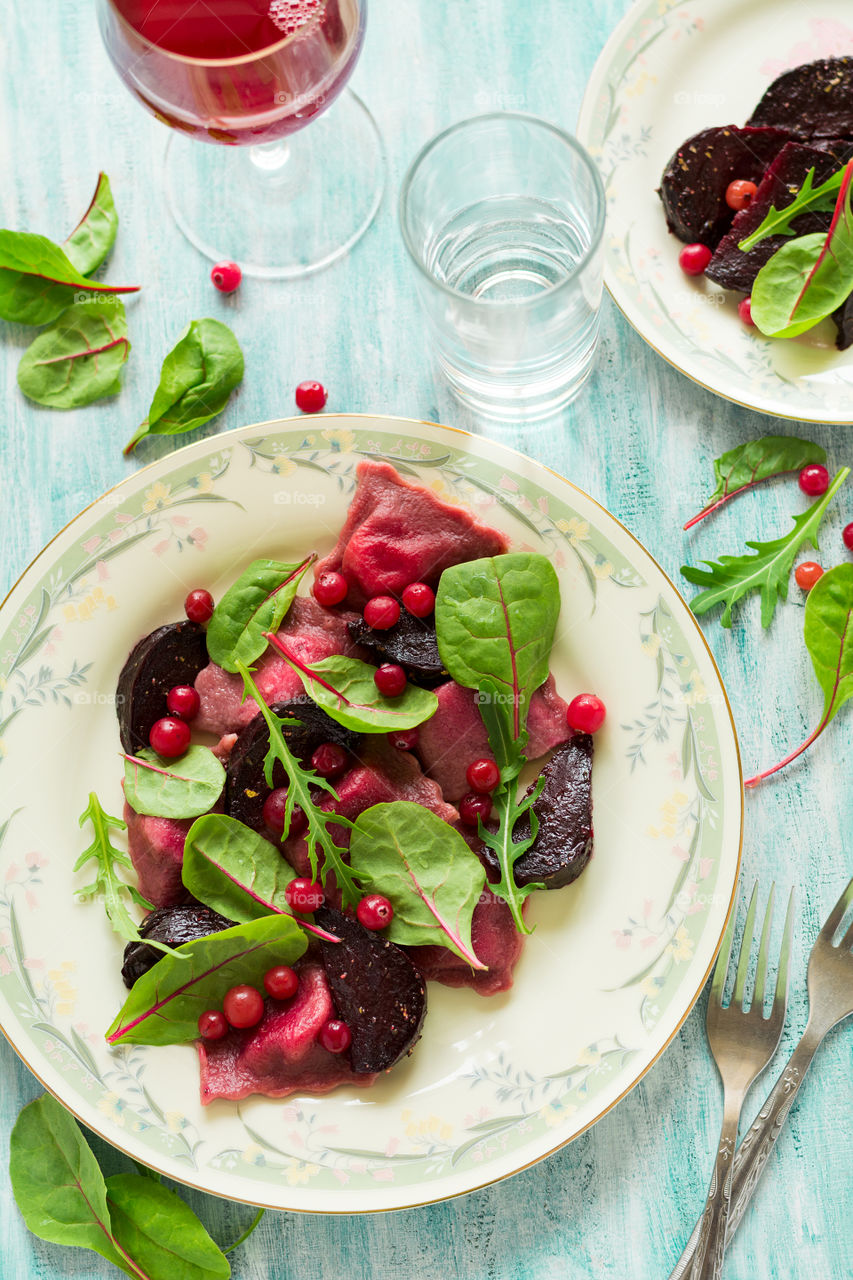 Beetroot ravioli with beetroot slices, cranberry and salad mix