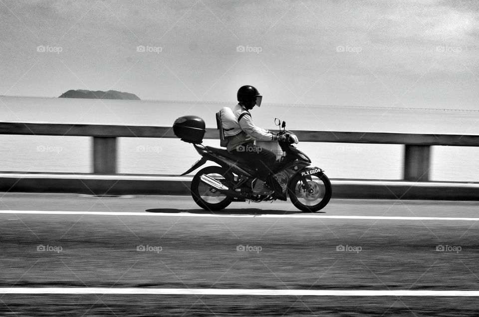 Motorcyclist. a motorcyclist riding same speed with our car at Penang Bridge