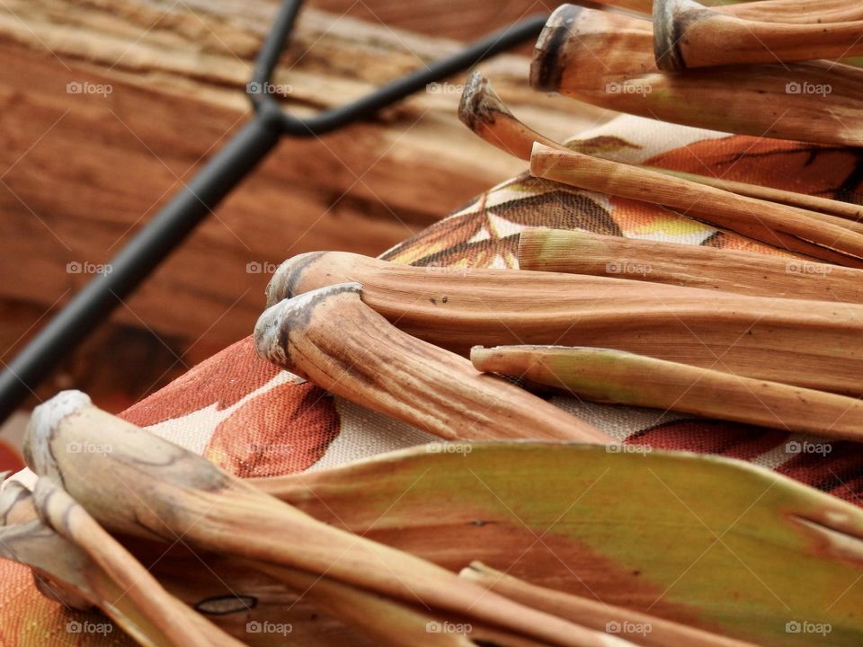 Autumn fall decor and cloth with logs and fire grate closeup with orange drawings of leaves, logs and dry palm leaves branches on a step.