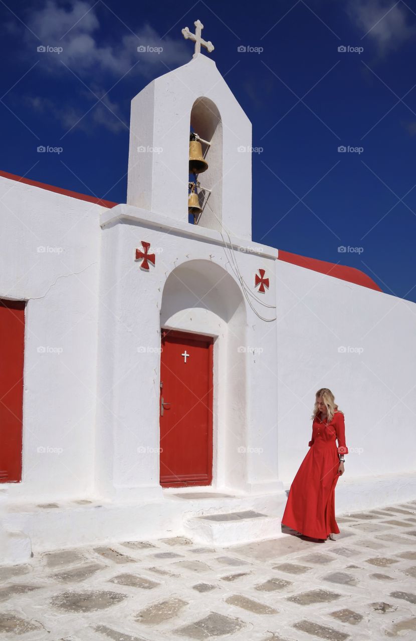 young woman in red dress near the temple with red door