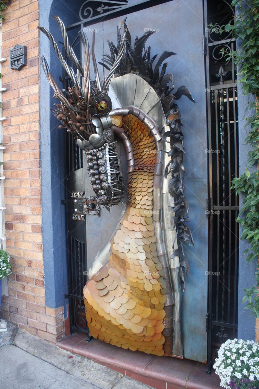 A crazy cool house door with a metal dragon on it in the artistic city of San Francisco 