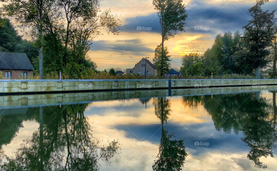 Colorful painterly autumn sky reflected in the water of a river or canal flowing through a natural Countryside area