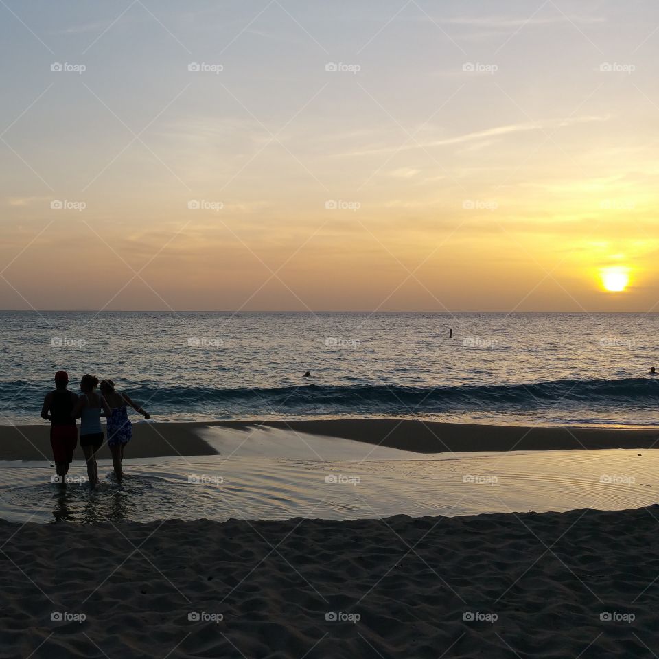 Silhouette of people standing on beach against dramatic sky