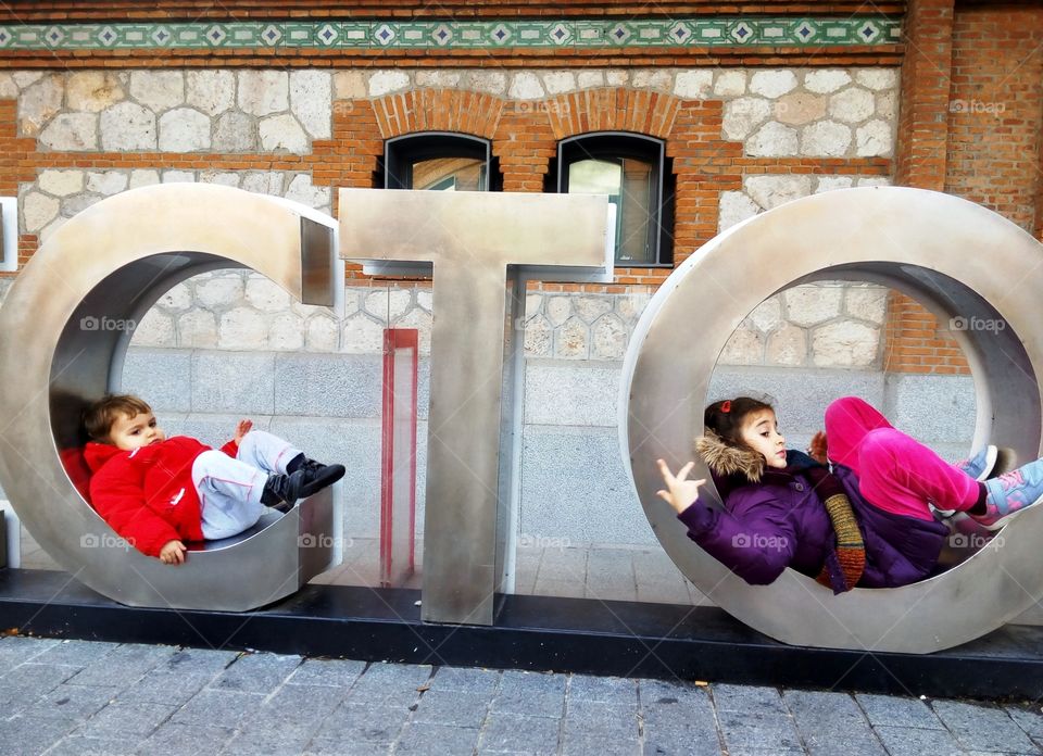 two girls lie down on the letters