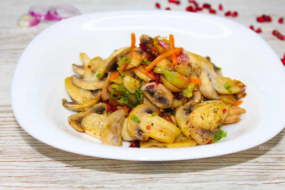 Stewed mushrooms with vegetables on a white plate