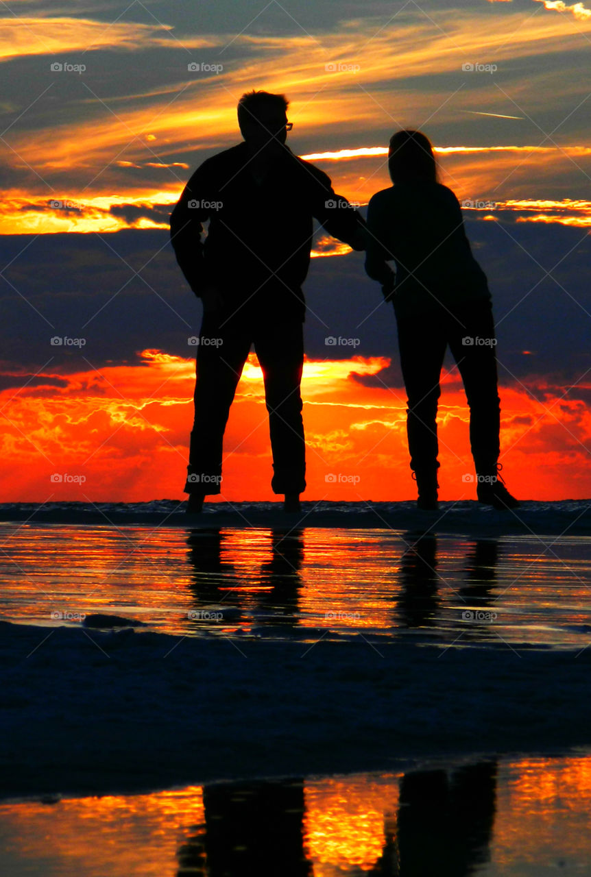 Couple strolling the sandy beach on the Gulf of Mexico,Florida,enjoying the ocean breeze and the spectacular sunset!