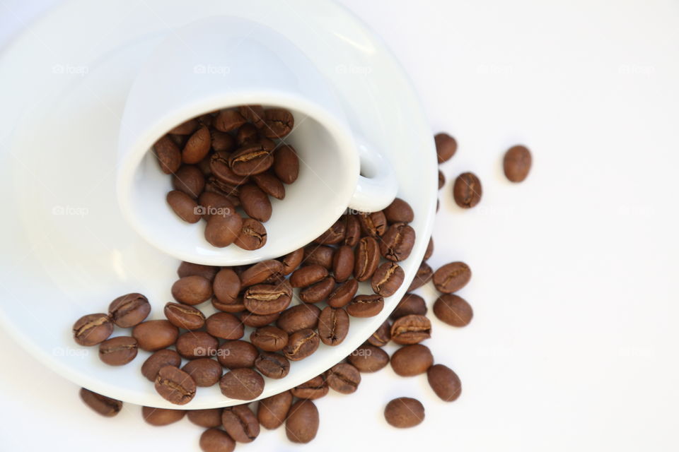 Roasted coffee beans with a cup on white background