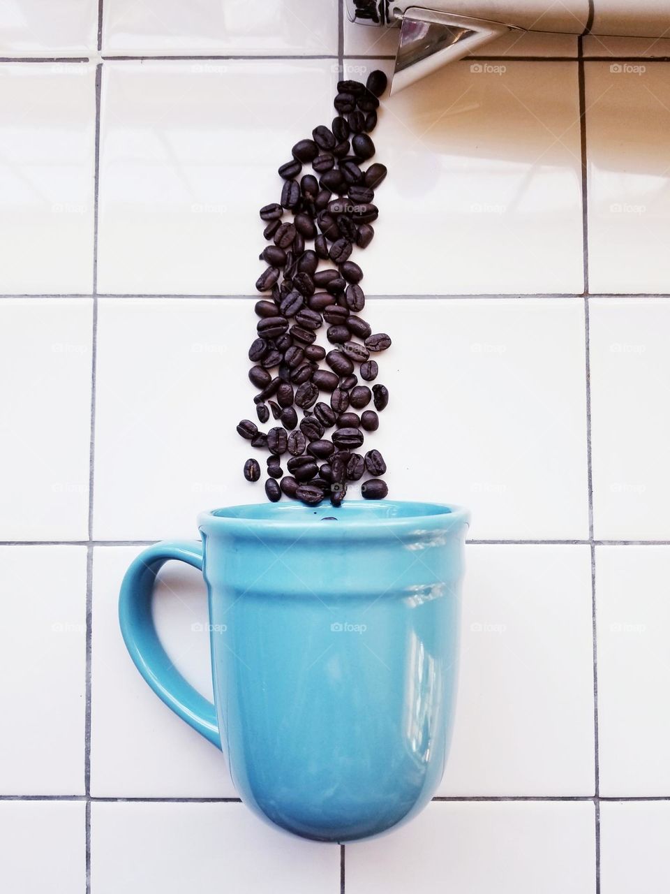 Coffee Beans being Poured into a Blue Mug from a Percolator from above