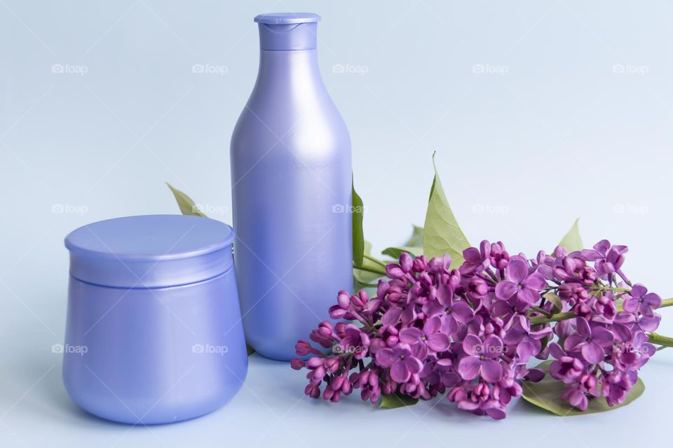 Spring, purple fragrant lilac with green leaves.  and jars with cosmetic cream and product.