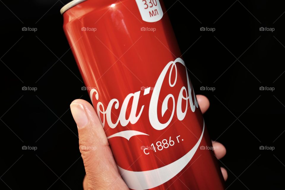 coca cola in hand black background close up, drinking coca cola,