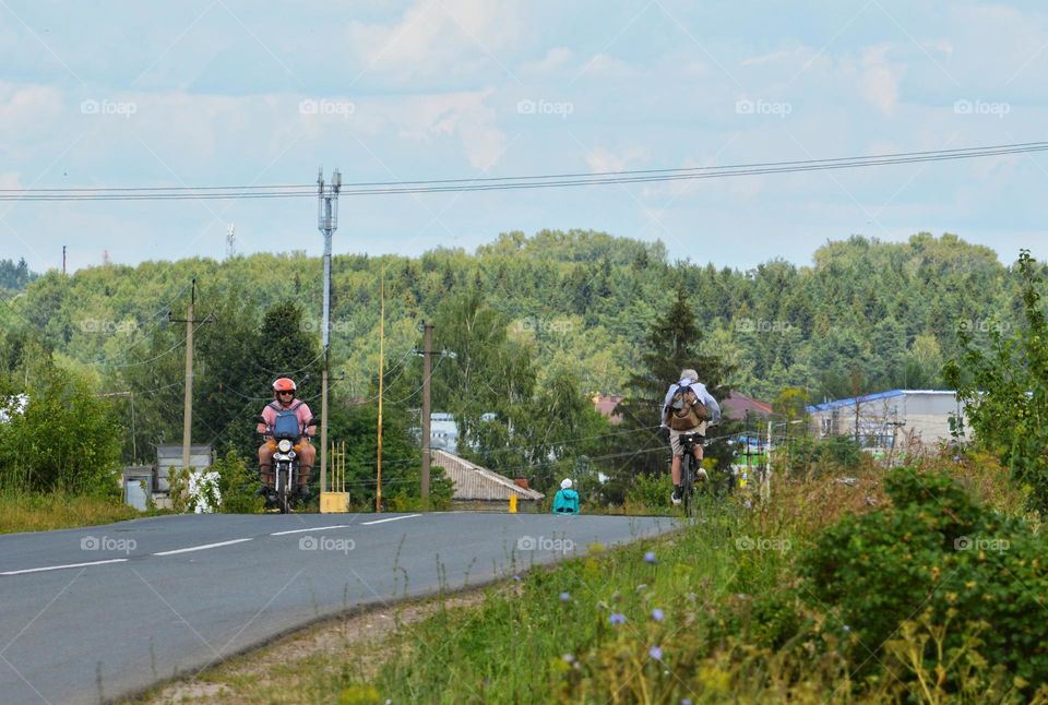 landscape near the road along which the traveler is riding a cyclist and on the other side is a motorcyclist