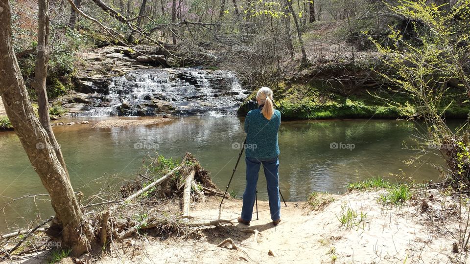 Woman amateur photographer at waterfall