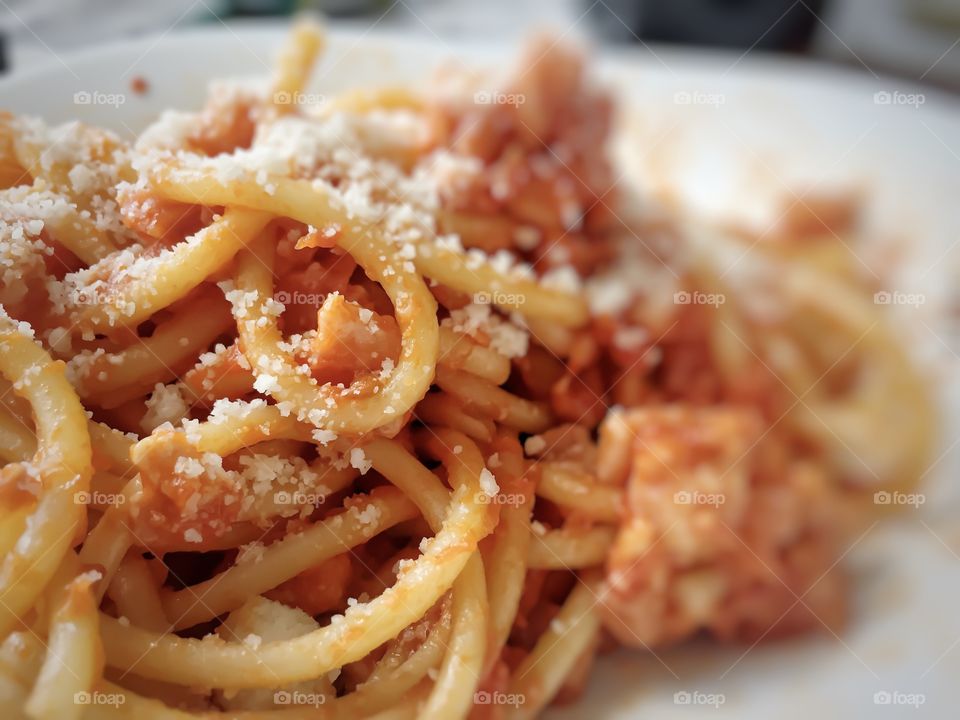 Homemade pasta bucatini amatriciana with tomato sauce, cured pork cheek and grated pecorino cheese 