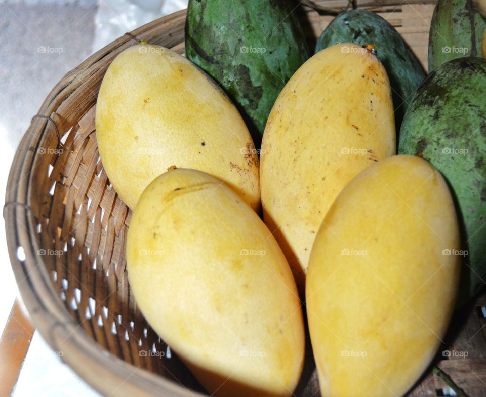 Ripe and green mangoes in the basket