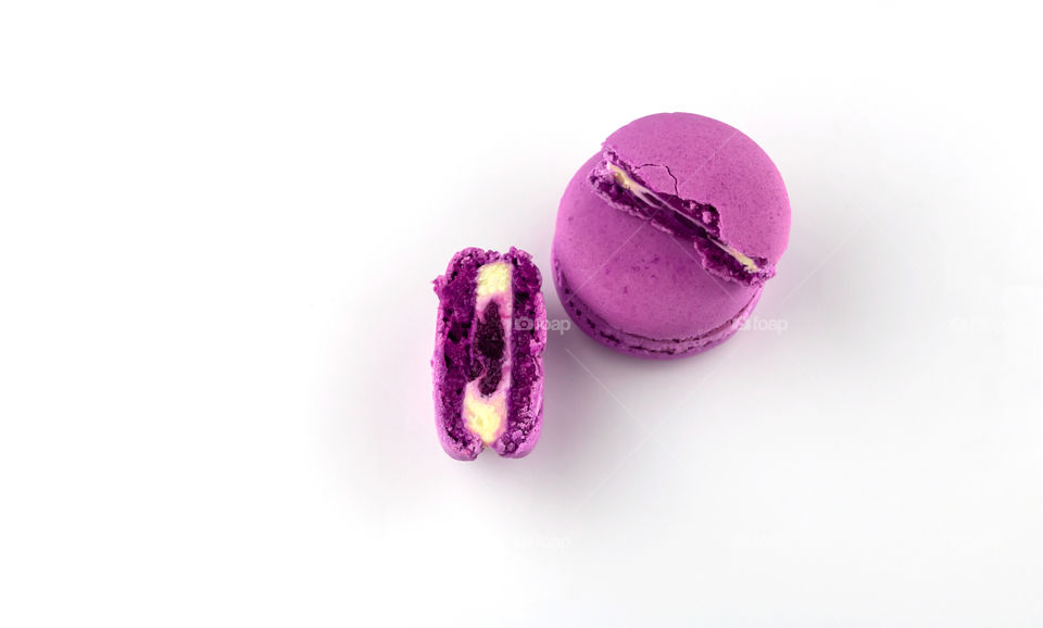 Purple macarons with cream and fruits on white background. Copy space.