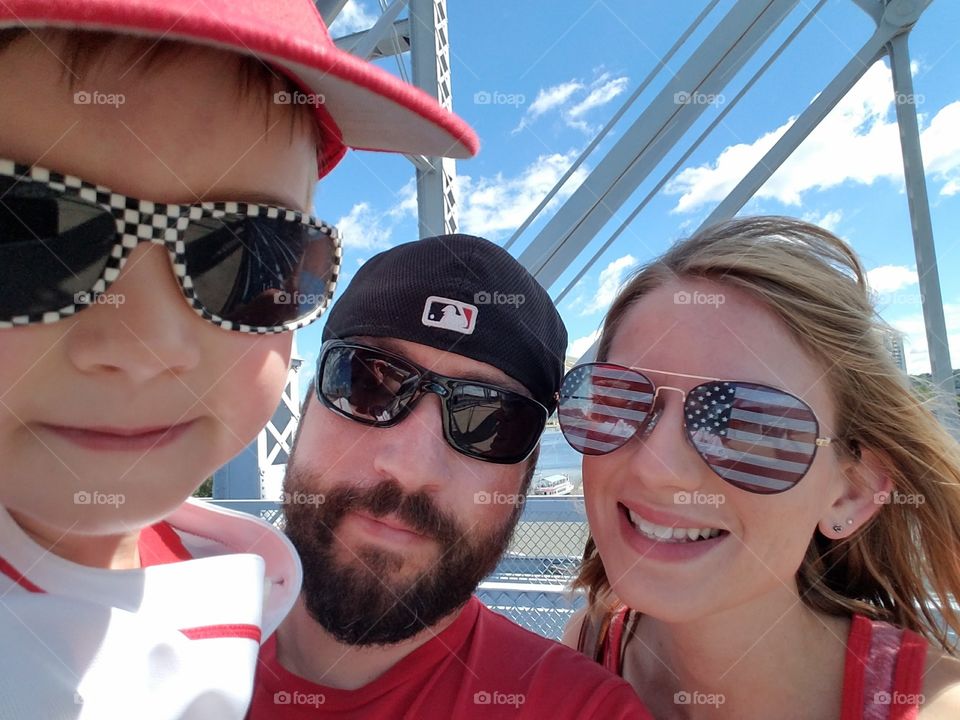 Family selfie on a bridge with a bright blue sky background during the summer