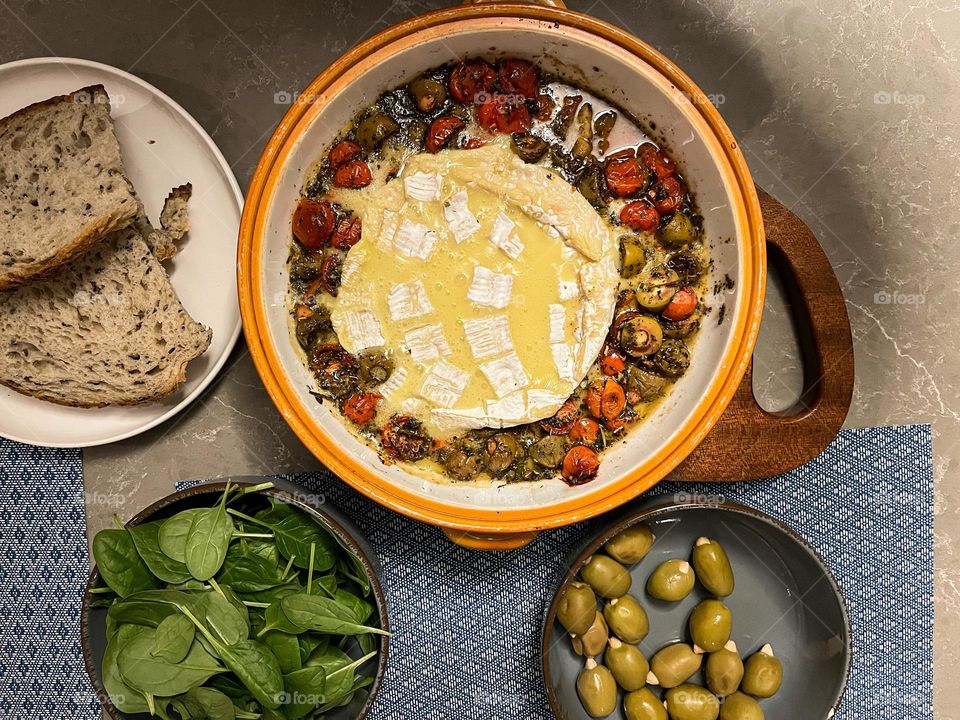 Home cooked meal. Brie cheese with olives, tomatoes fresh bread and baby spinach.