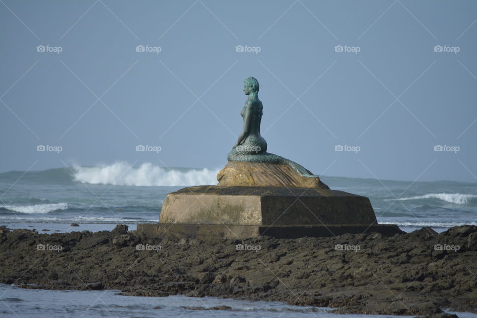 Mermaid Statue  by the Sea warns boats of rocks located on shore in the small Fishing Village of Esterillo O Este Coasta Rica.