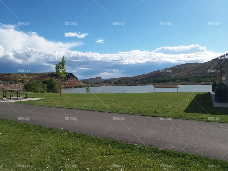 sky clouds lake grass pavement