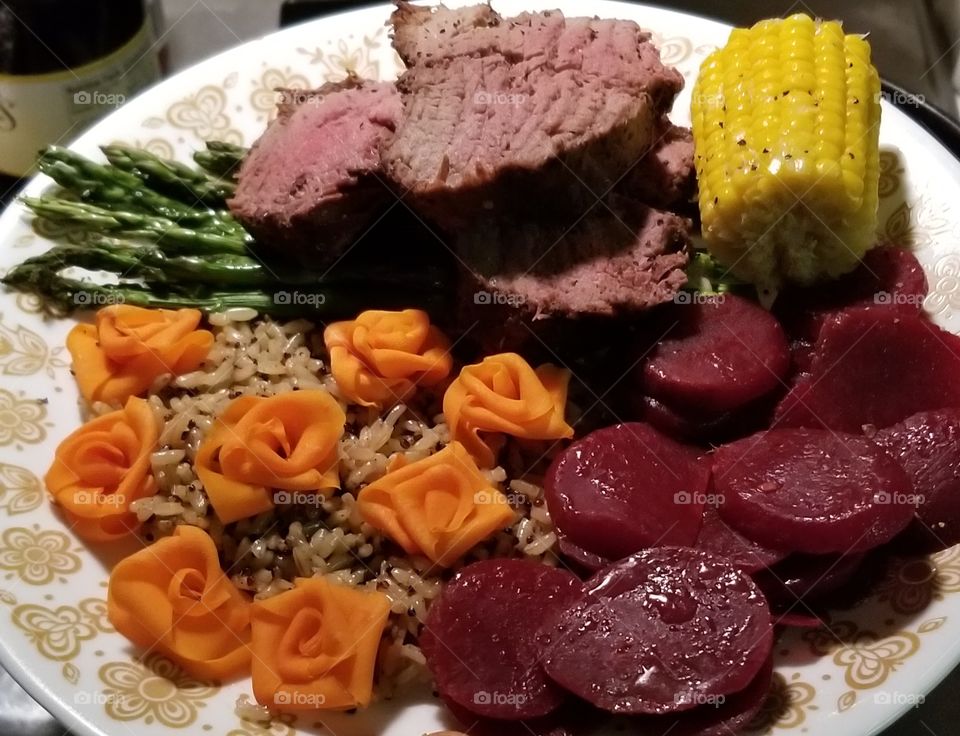 Christmas dinner of beef tenderloin, quinoa, corn, asparagus, and carrot roses.