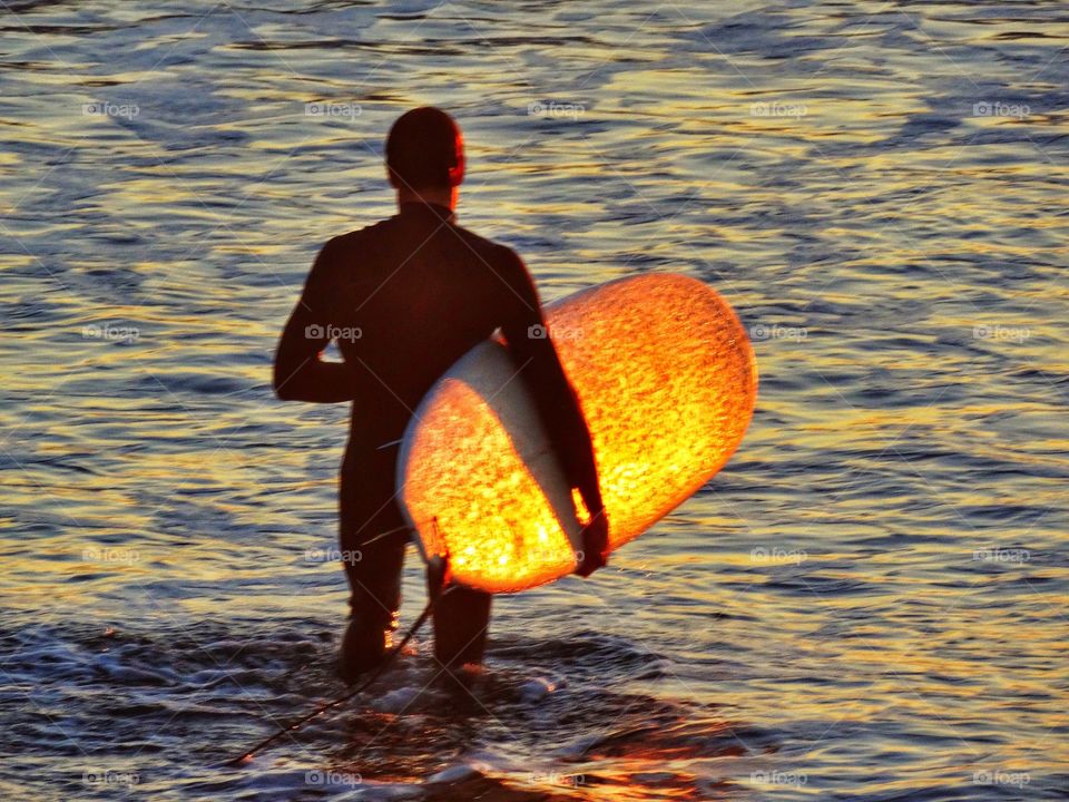 Longboard rider entering the water in Half Moon Bay, California
