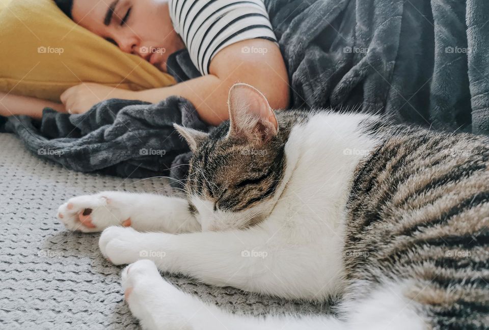 Close-up photo of woman and cat taking a nap on couch