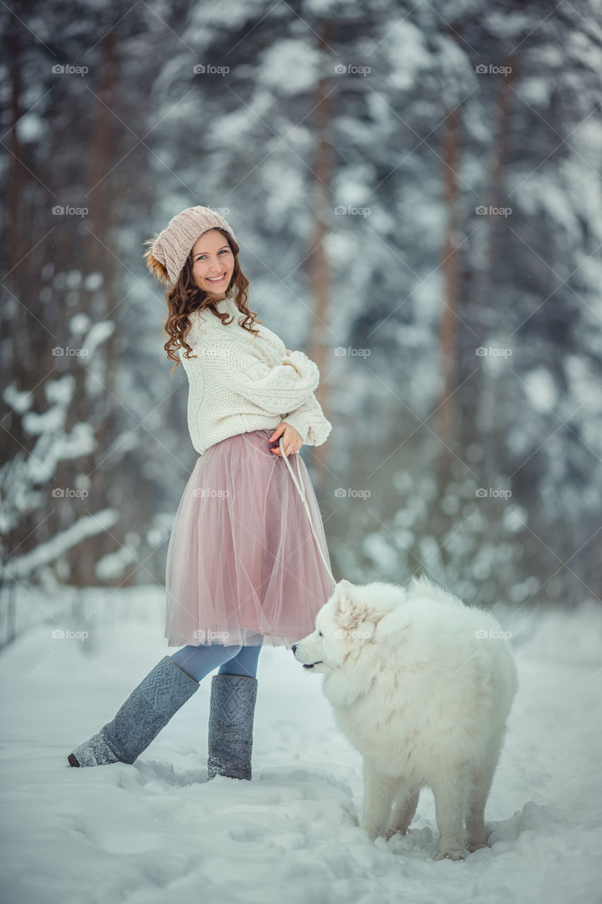 Beautiful woman with dog samoyed in winter forest