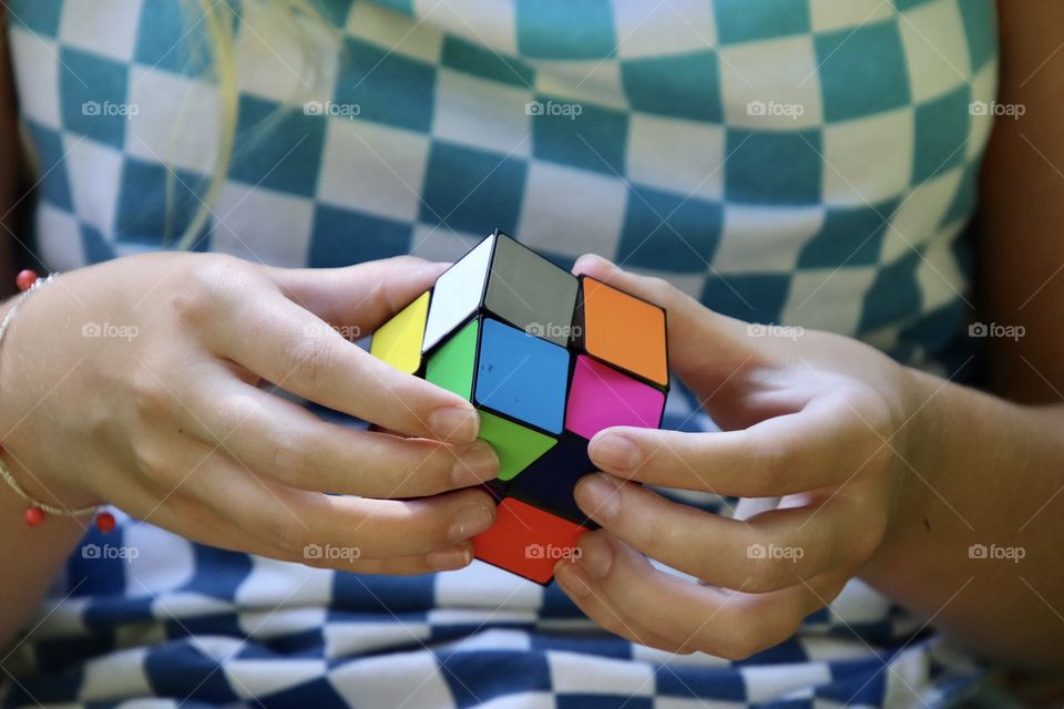 Girl wearing checkered shirt while holding colorful cube 