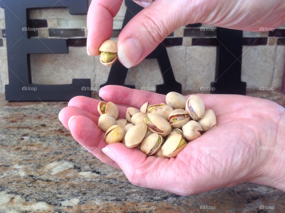 Holding a handful of pistachio nuts.