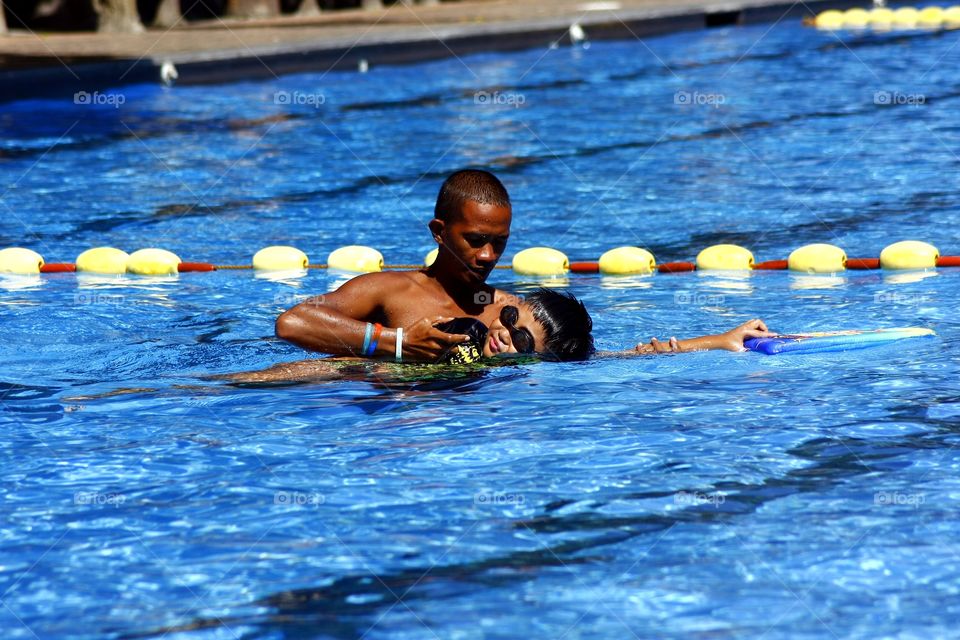 coach teaching a teen how to swim