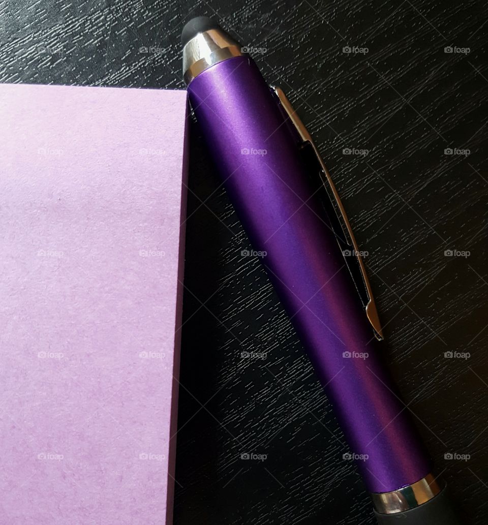 purple paper and pen on black desktop