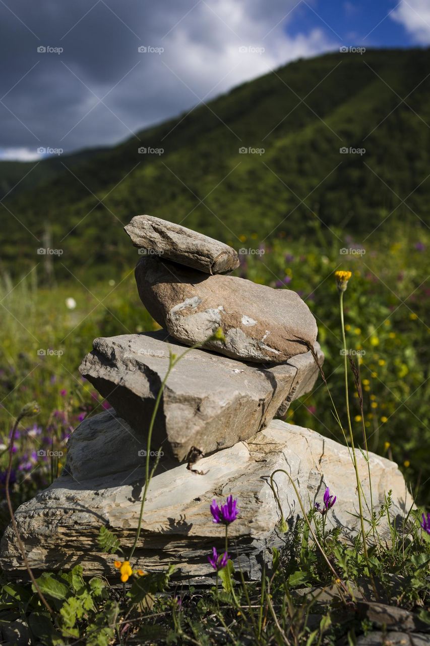 Stone stack with balanced stones on blurred mountain background. Vertical shot