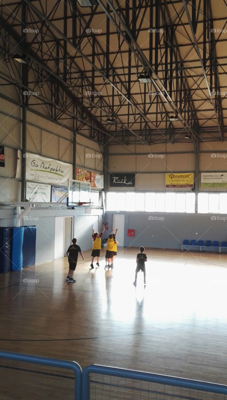 school children playing basketball inside hall