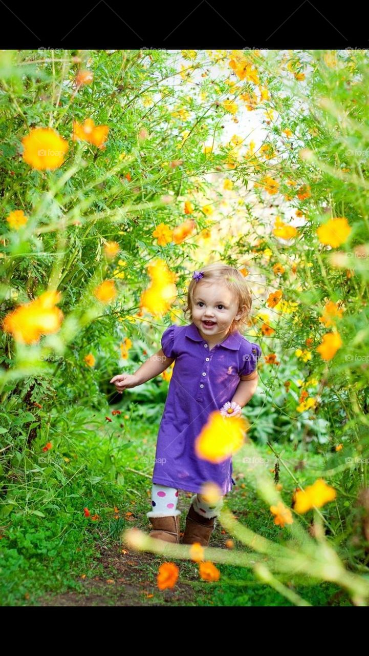 Little girl running through a patch of yellow wild flowers